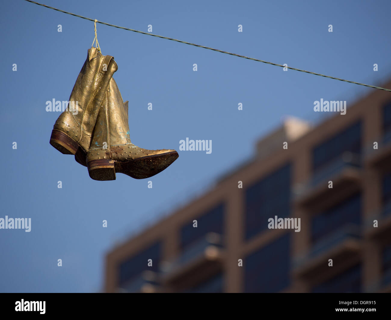 Golden cowboy boots hanging from an electrical wire in Austin, Texas Stock Photo