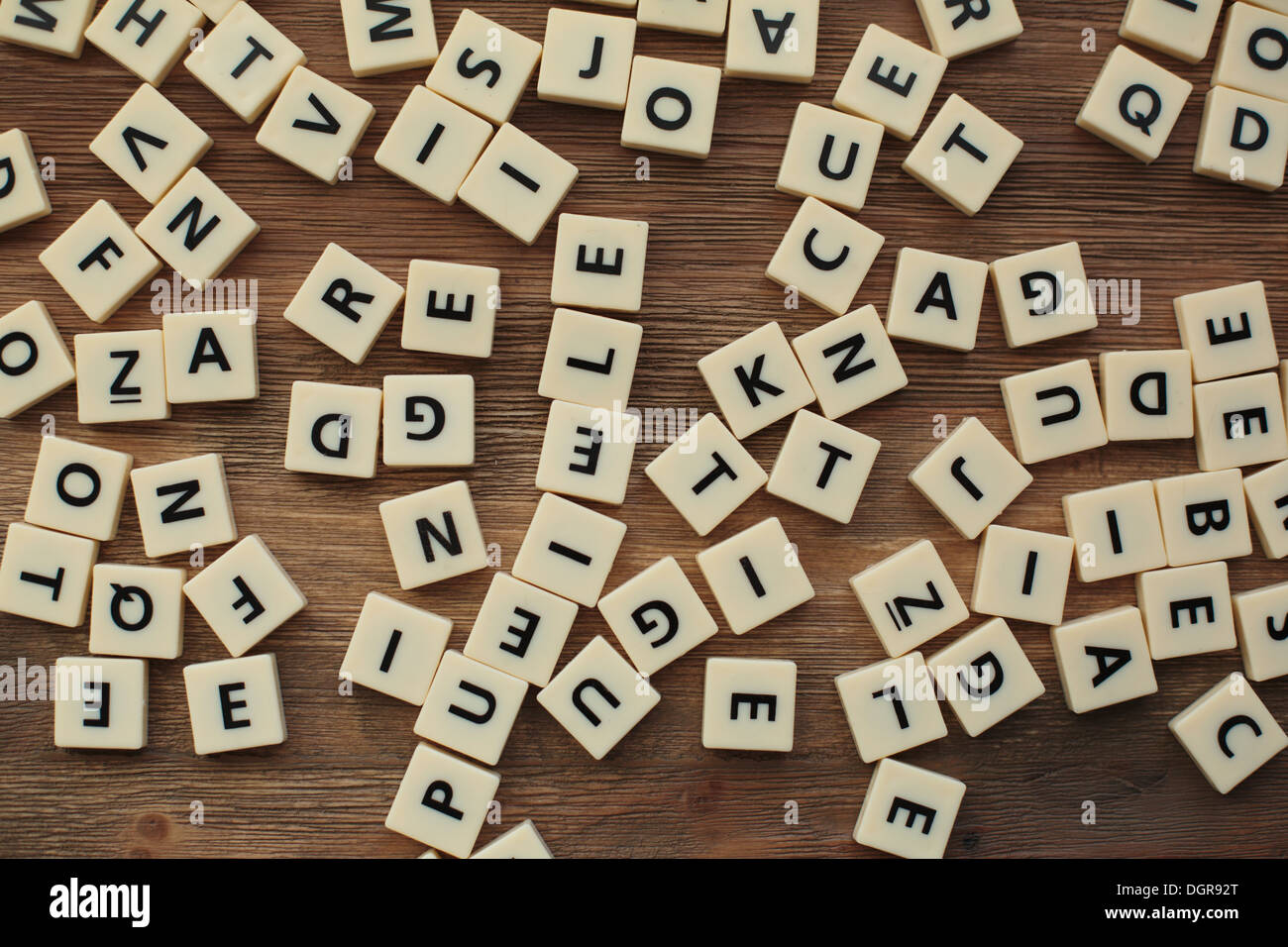 Plastic letters from a children's spelling game, jumbled on a wooden table Stock Photo