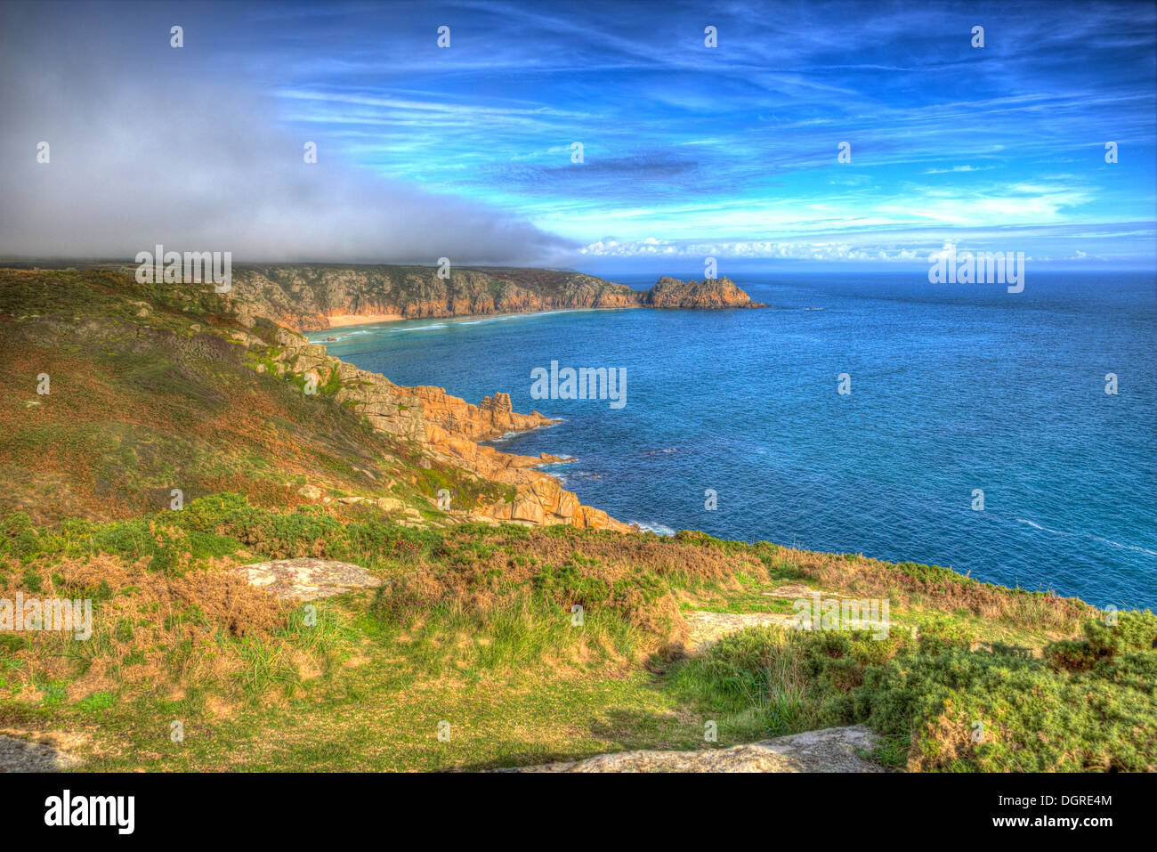 Cornwall coast with low cloud and mist yet blue sky in HDR with blue sea Stock Photo