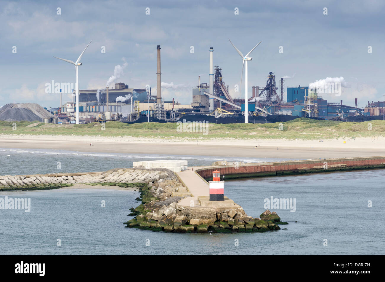 Lighthouse at the harbor entrance of Ijmuiden, wind turbines and the Tata steel plant at the back, North Holland, Netherlands Stock Photo