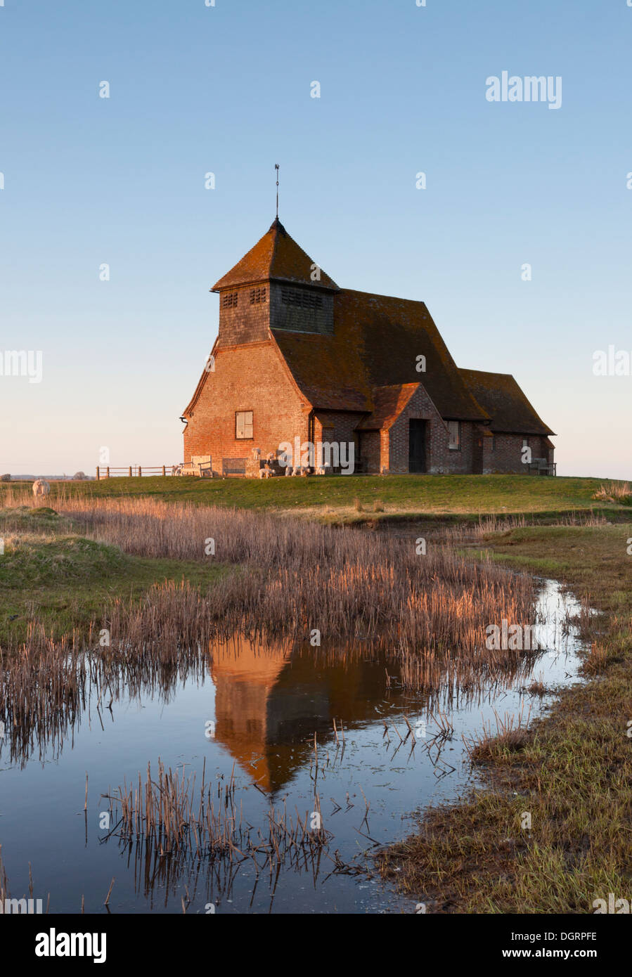 The Church of St Thomas a Becket, in Fairfield, Kent; reflected in the marshes at sunset. Stock Photo