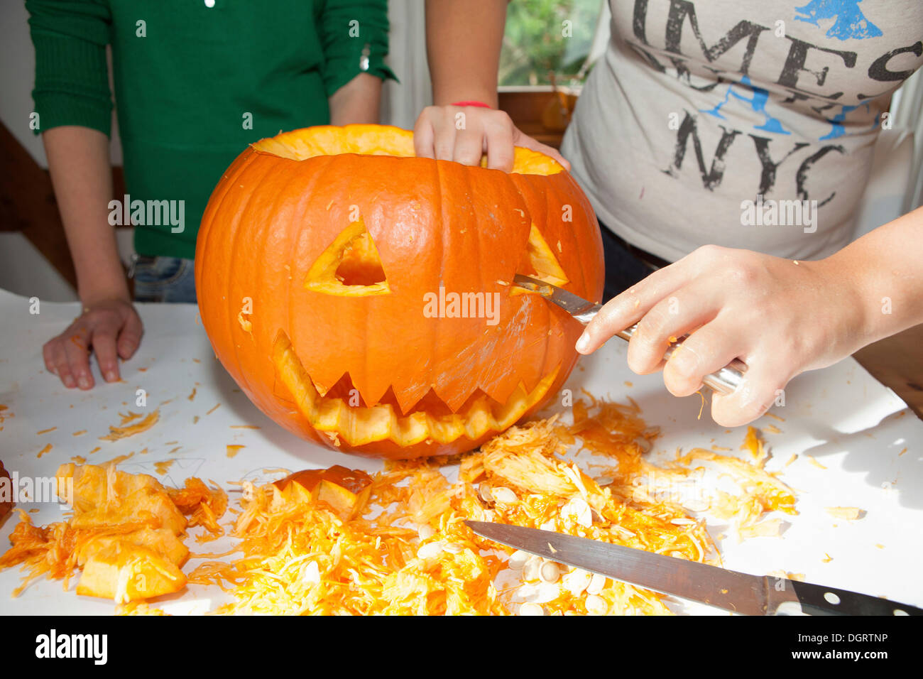 Two girls, about 14 years, carving a face into a Halloween pumpkin Stock Photo