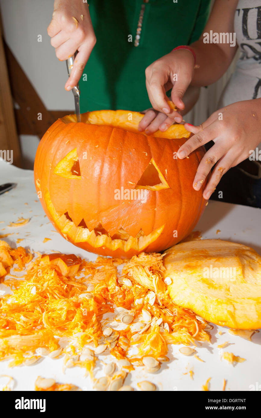 Two girls, about 14 years, carving a face into a Halloween pumpkin Stock Photo