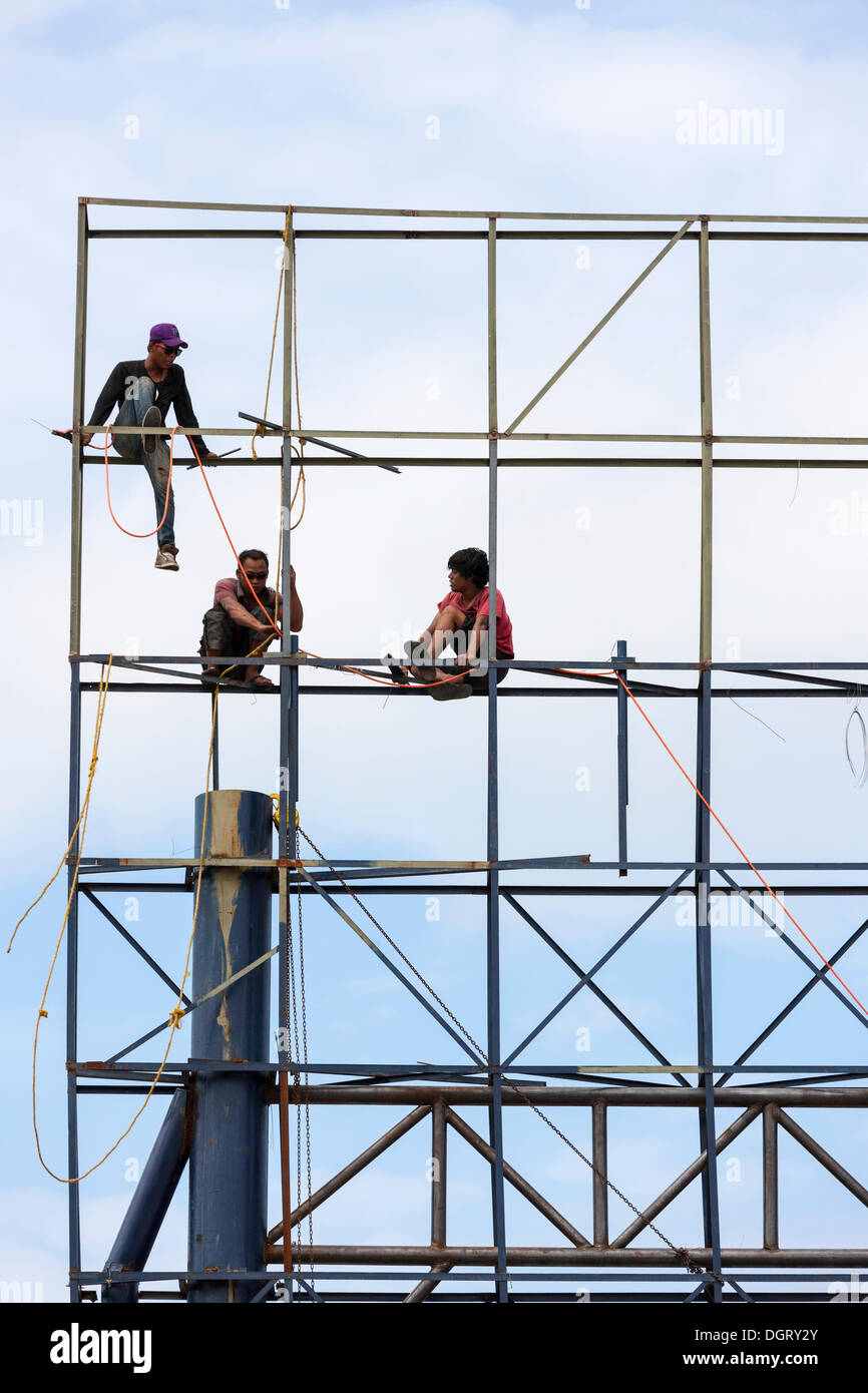 Unsecured workers assembling scaffolding, Banjar Kertabuana, Denpasar, Bali, Indonesia Stock Photo
