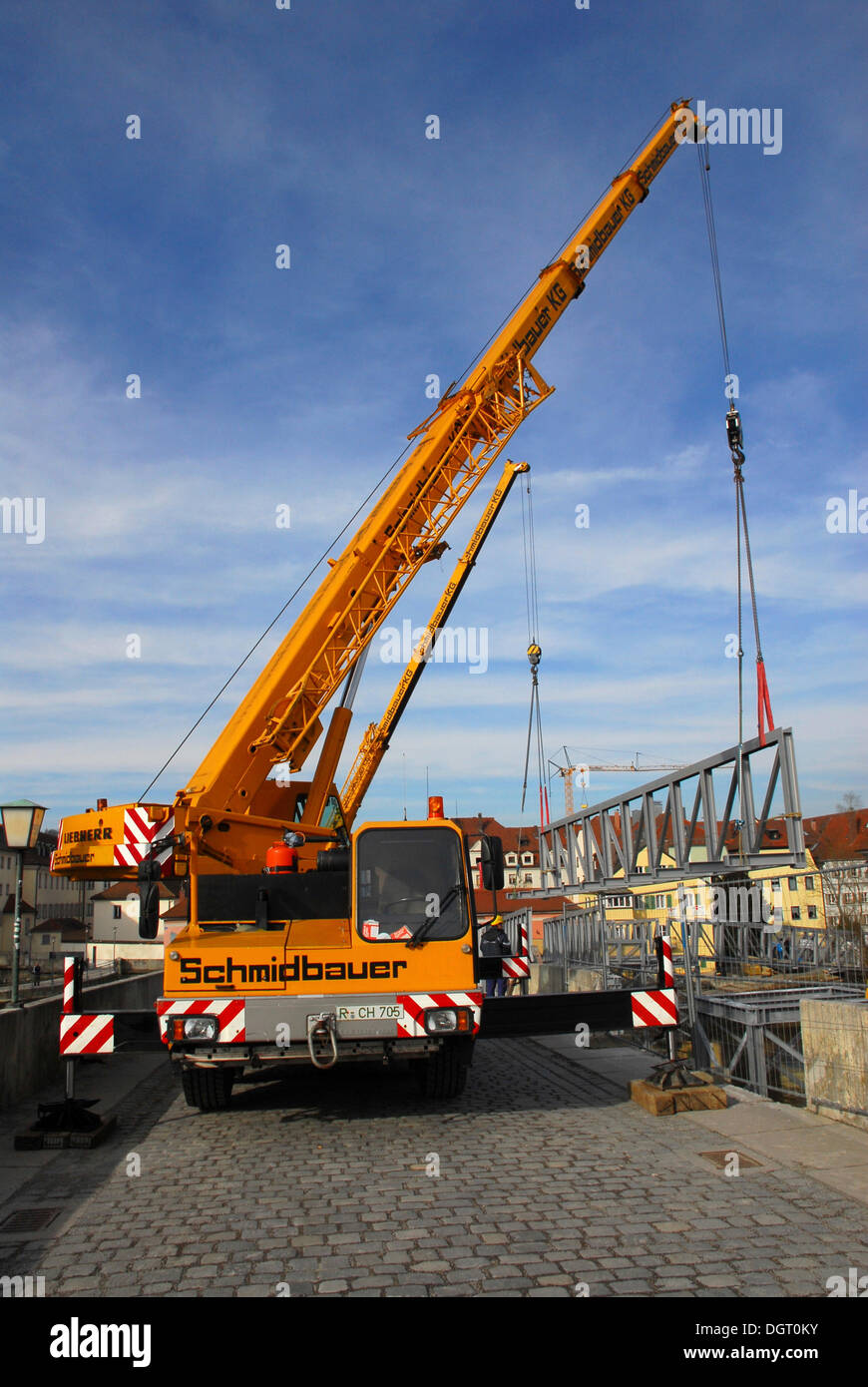 Two cranes lifting steel beams on Steinerne Bruecke, a stone bridge