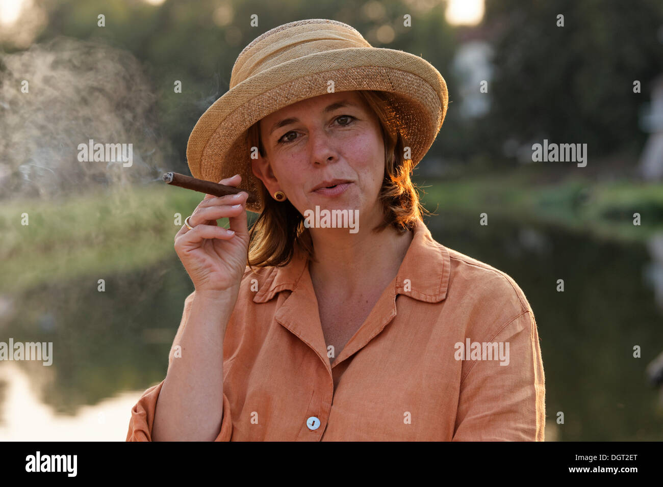 Woman smoking a cigar on a houseboat on the Canal des Vosges, formerly Canal de l'Est, evening mood, Selles, Vesoul Stock Photo