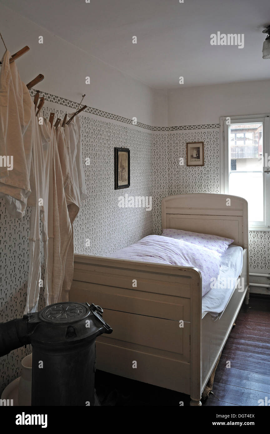 Bedroom of the early 20th century with a bed, a potbelly stove and a laundry line on the left, industrial museum, Lauf Stock Photo