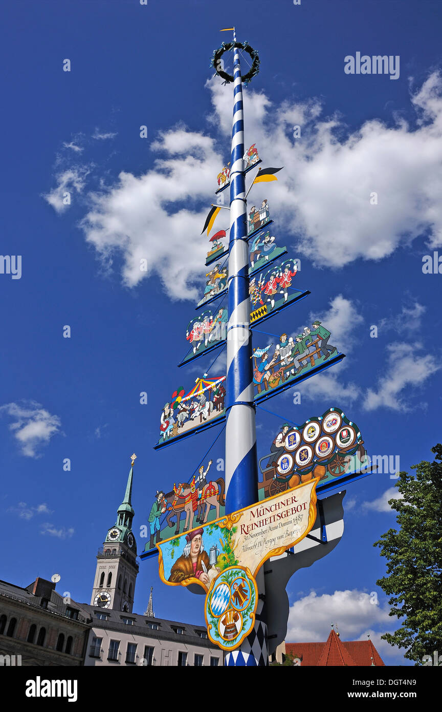 Maypole on Viktualienmarkt market against blue sky with clouds, steeple of the Church of St. Peter at the back, Munich, Bavaria Stock Photo