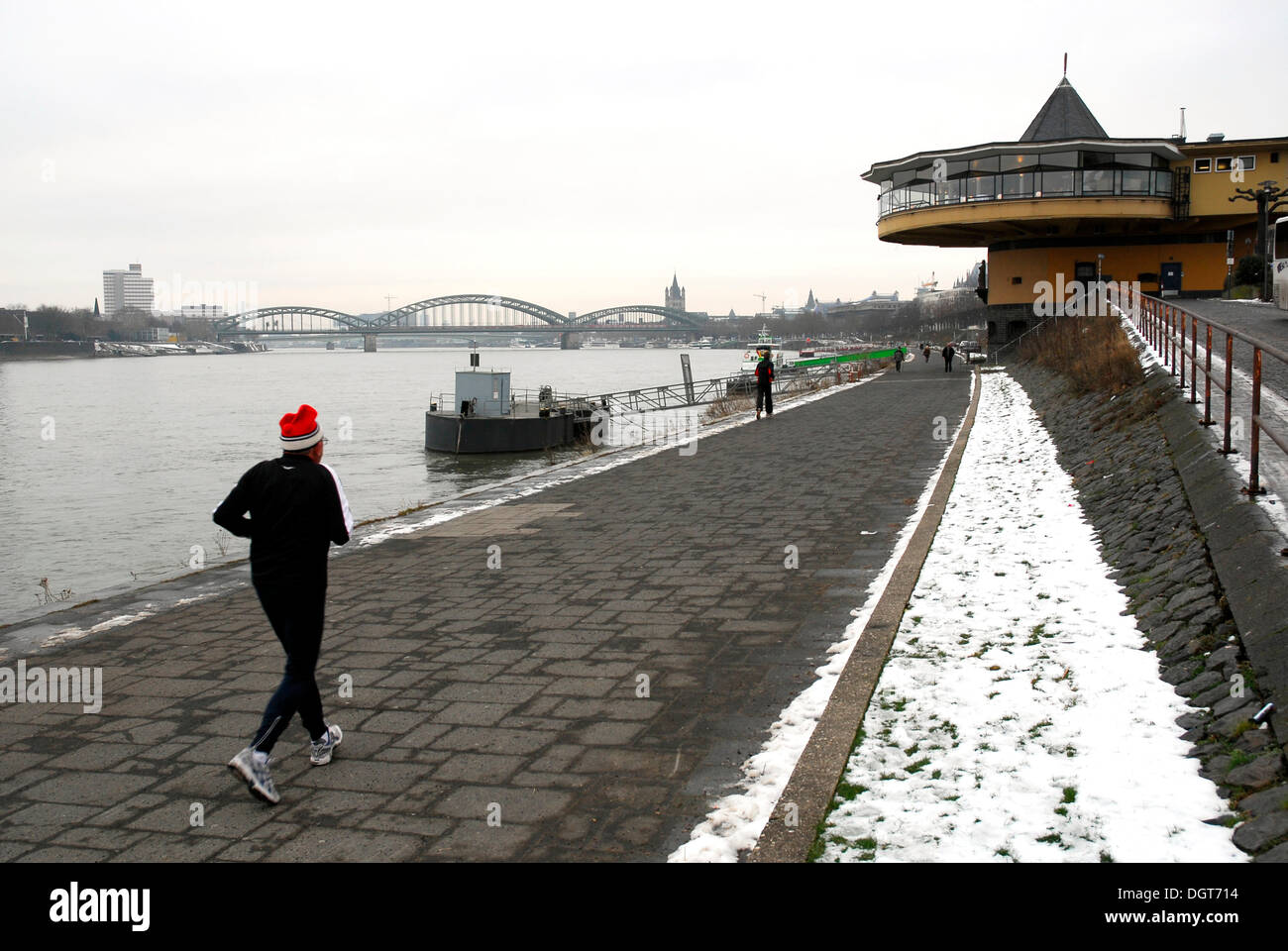 Jogger in winter, promenade between the river and the Konrad-Adenauer-Ufer shore, in the back the Bastei restaurant on the Rhine Stock Photo