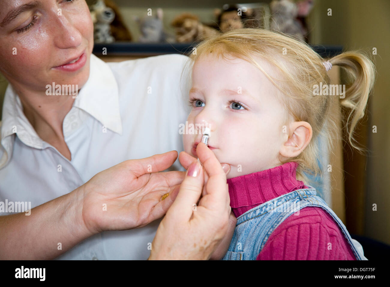 Three and a half year old child, accompanied by her mum / mother, receives a dose of the new flu vaccine - Fluenz - in the form of a nasal spray immunisation from her NHS GP Practice nurse. UK. Stock Photo