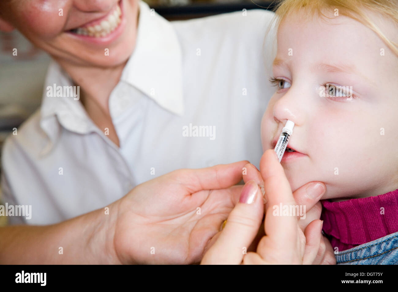 Three and a half year old child, accompanied by her mum / mother, receives a dose of the new flu vaccine - Fluenz - in the form of a nasal spray immunisation from her NHS GP Practice nurse. UK. Stock Photo