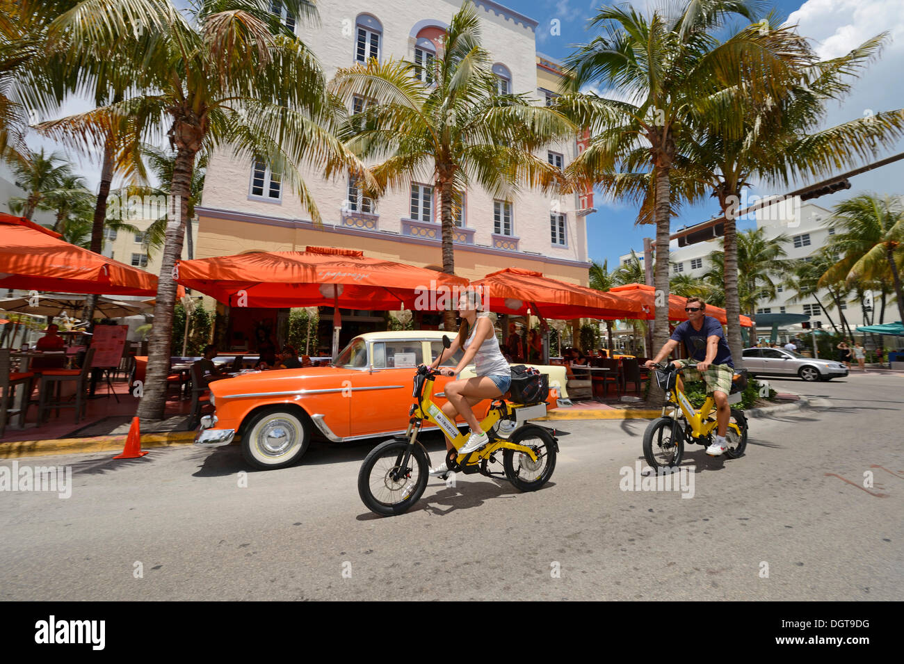 Couple riding electric bicycles, Ocean Drive, South Beach, Miami, Florida, USA Stock Photo