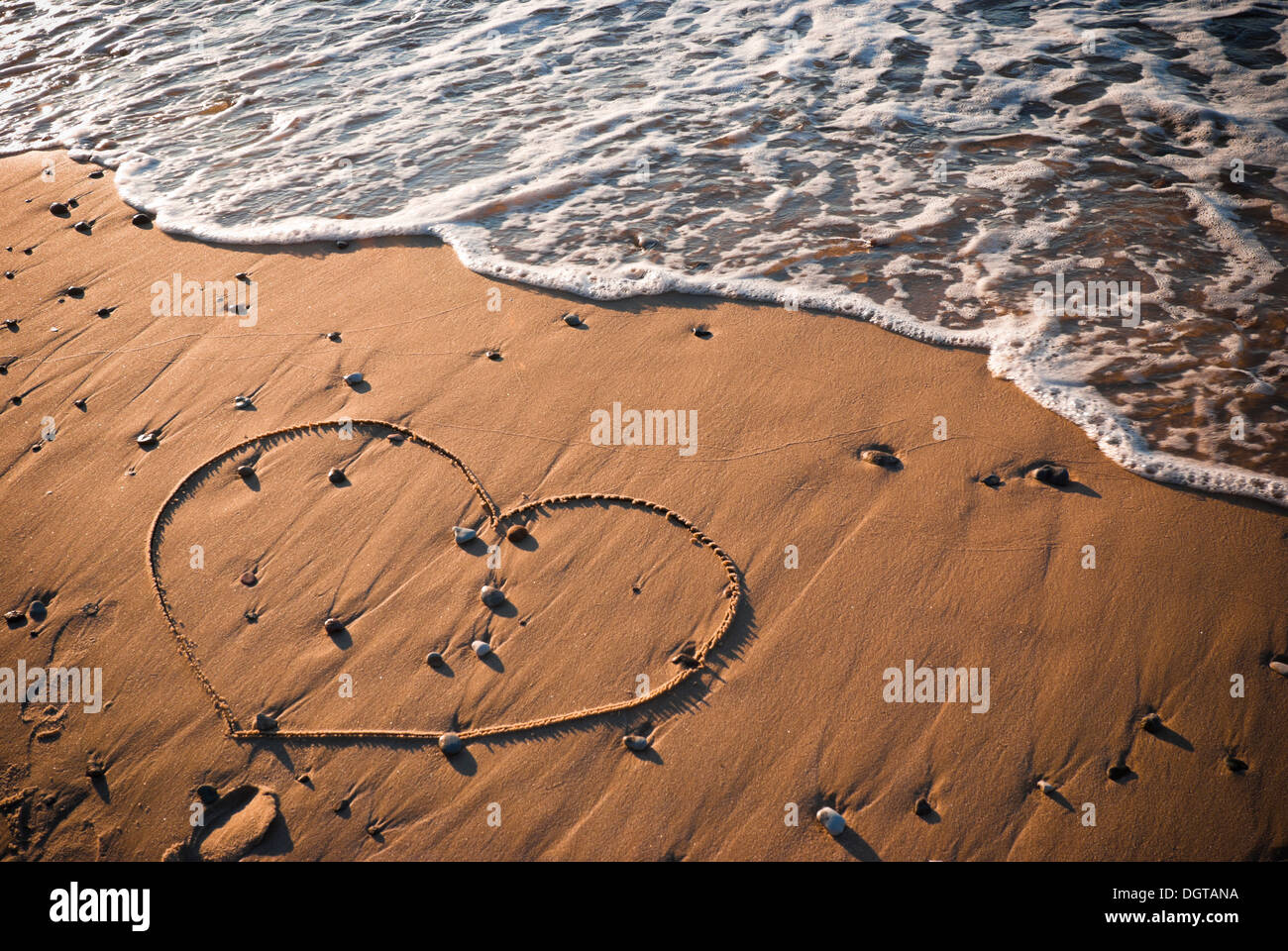 Heart shape written on sand with water in background Stock Photo