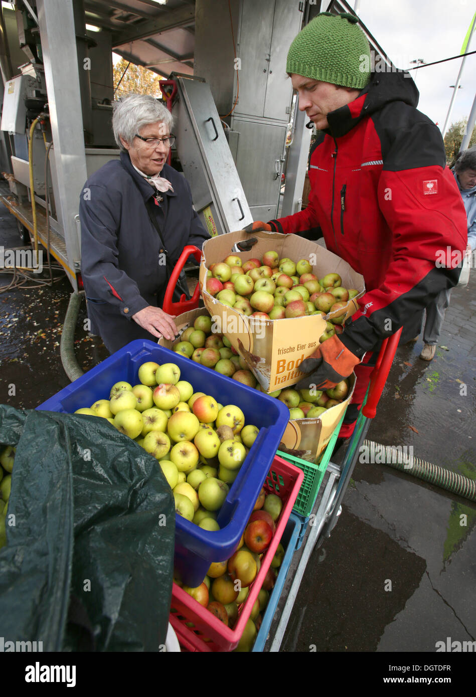 Rostock, Germany. 21st Oct, 2013. Benjamin Peters (R) helps his customers unloading apples at the mobile apple-juice factory of the apple-juice factory Satow in Rostock, Germany, 21 October 2013. The facility which is moved to another town in the region every day can process up to 4,000 kilos a day. Photo: Bernd Wuestneck/ZB/dpa/Alamy Live News Stock Photo