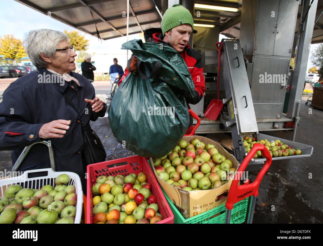 Rostock, Germany. 21st Oct, 2013. Benjamin Peters (R) helps his customers unloading apples at the mobile apple-juice factory of the apple-juice factory Satow in Rostock, Germany, 21 October 2013. The facility which is moved to another town in the region every day can process up to 4,000 kilos a day. Photo: Bernd Wuestneck/ZB/dpa/Alamy Live News Stock Photo