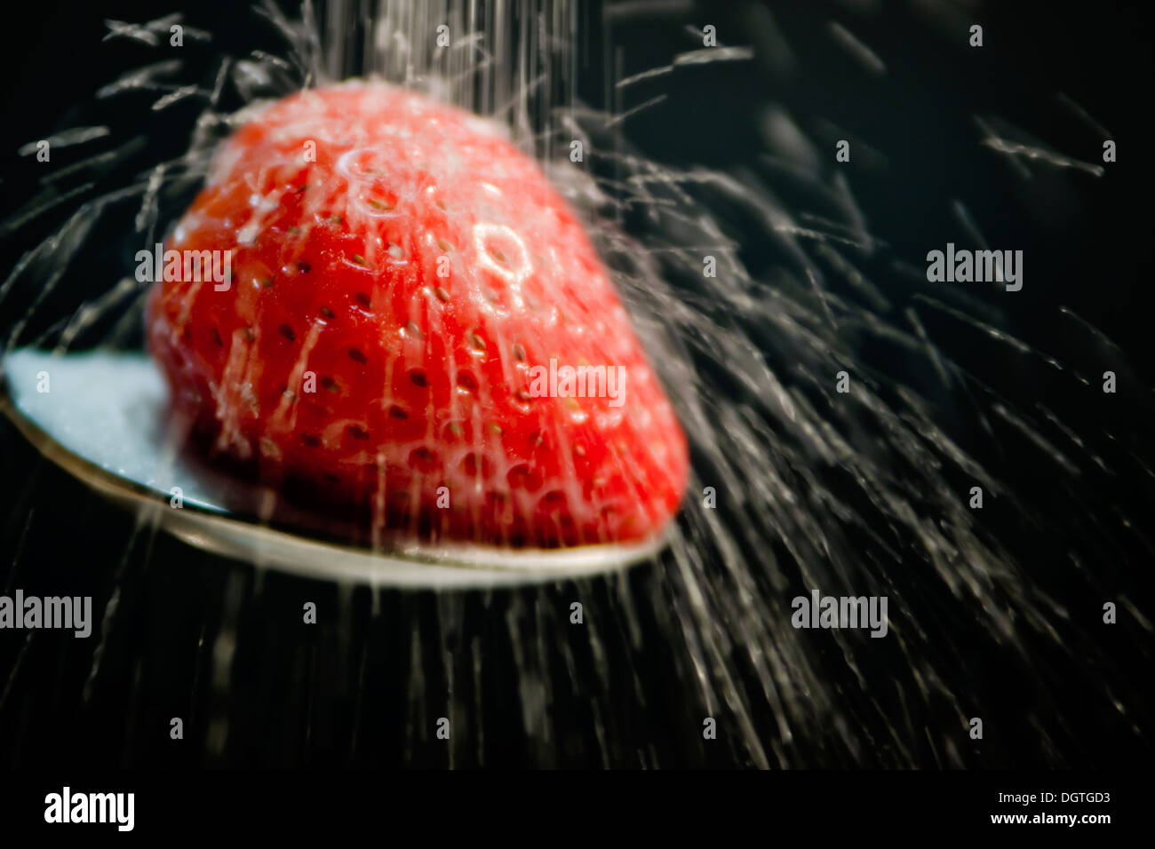 Strawberry on a spoon with sugar on black background Stock Photo - Alamy