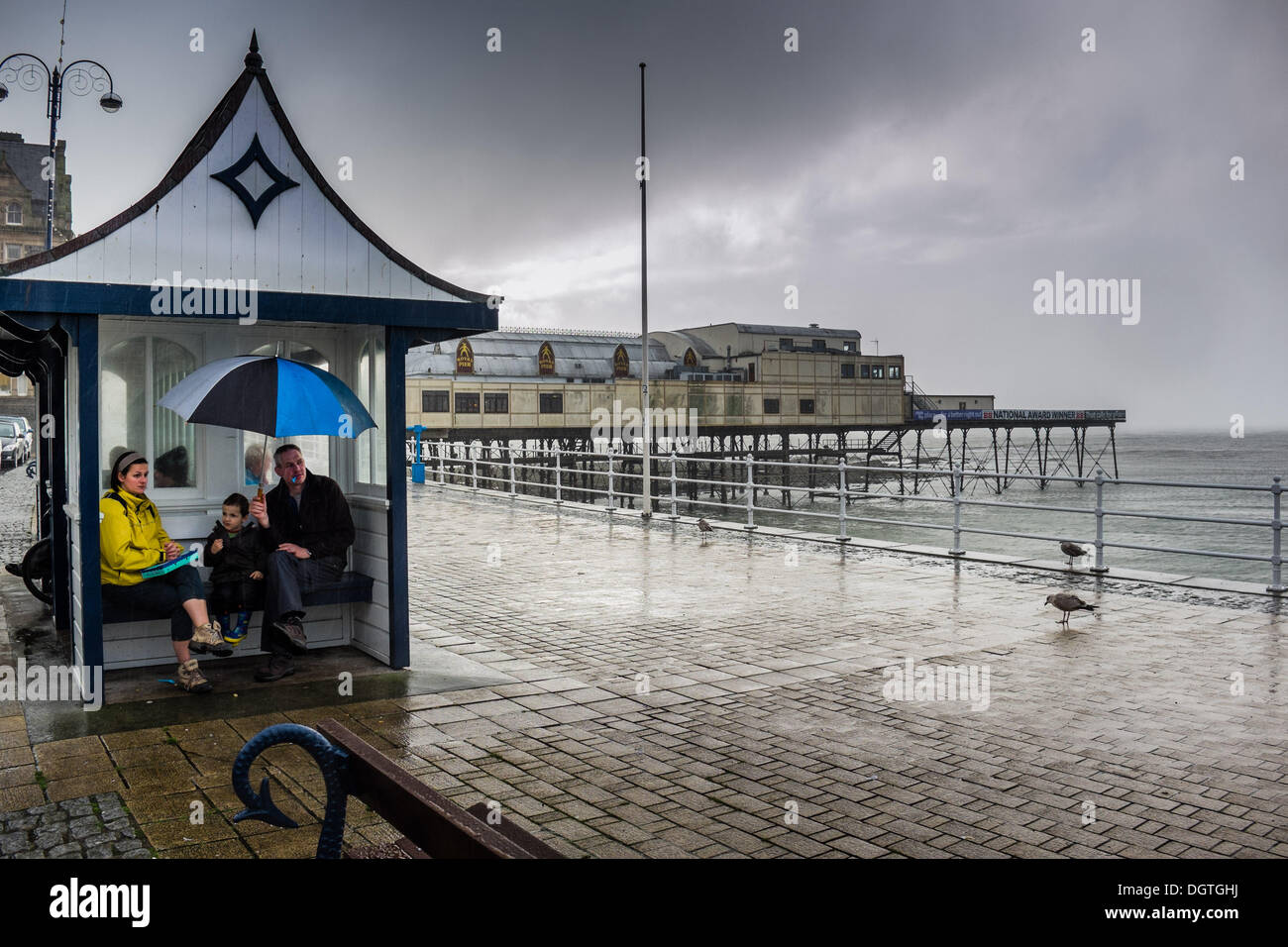 Aberystwyth Wales UK, October 25 2013 A family sheltering from the heavy thundery rain sweeping in off the sea at Aberystwyth in the west wales coast. The weather in the west and south of the UK is expected to turn dramatically stormier over the next 48 hours, with winds of up to 90mph forecast for many southern counties photo Credit:  keith morris/Alamy Live News Stock Photo