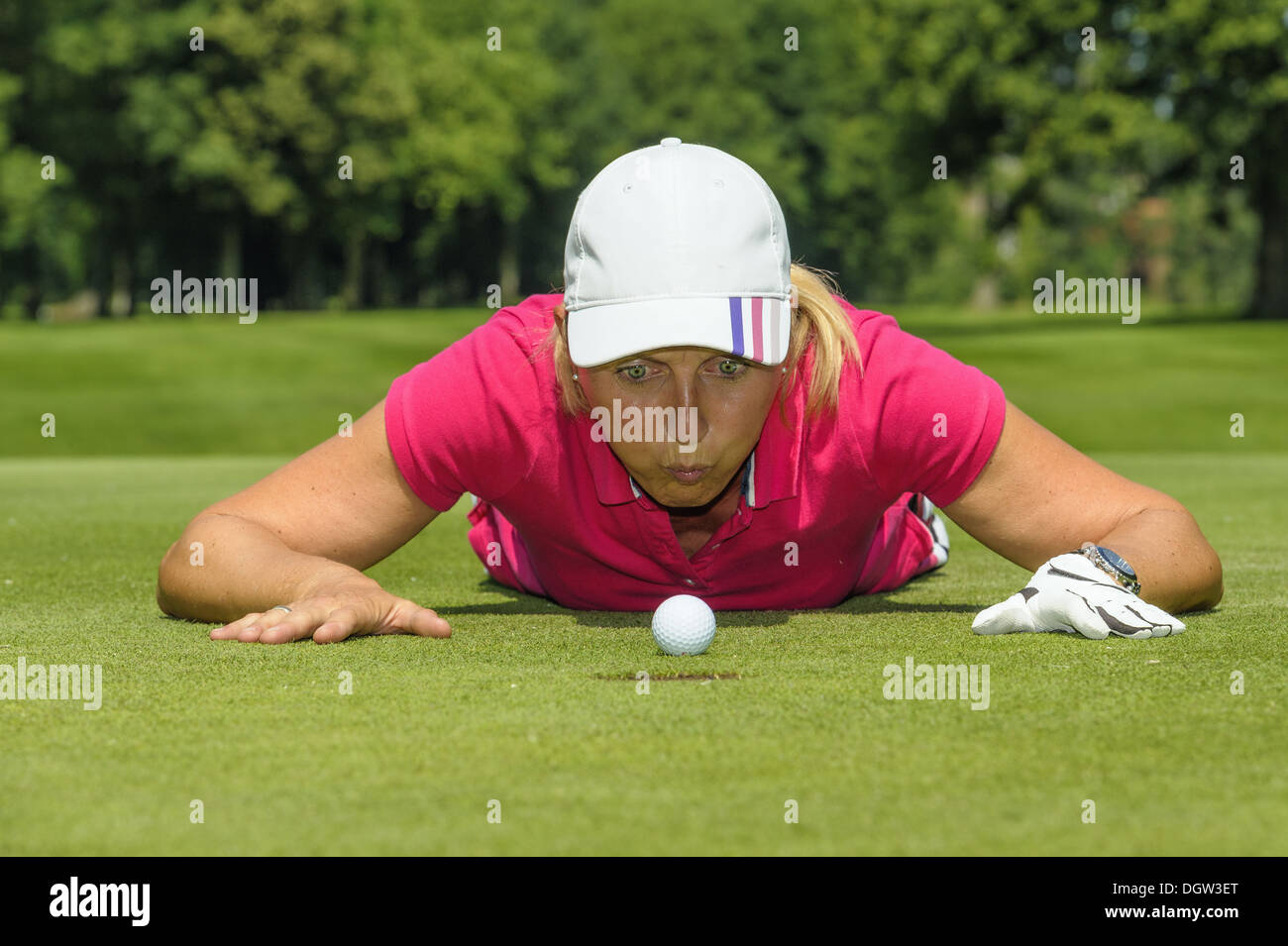 Golfer blowing golf ball into hole Stock Photo