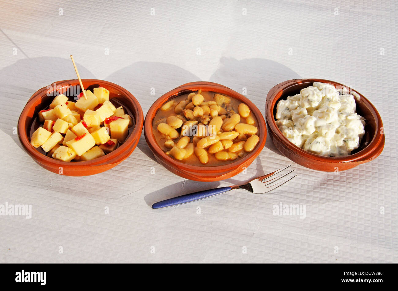 Spanish tapas comprising of Manchego with chill, Beans with pork, and Potato salad, Andalusia, Spain. Stock Photo