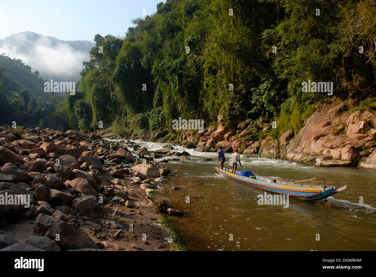 Wooden boat going upstream on the wild Nam Ou river, white water with rocks and jungle on the shore at Ban Sopkang, Phou Den Din Stock Photo