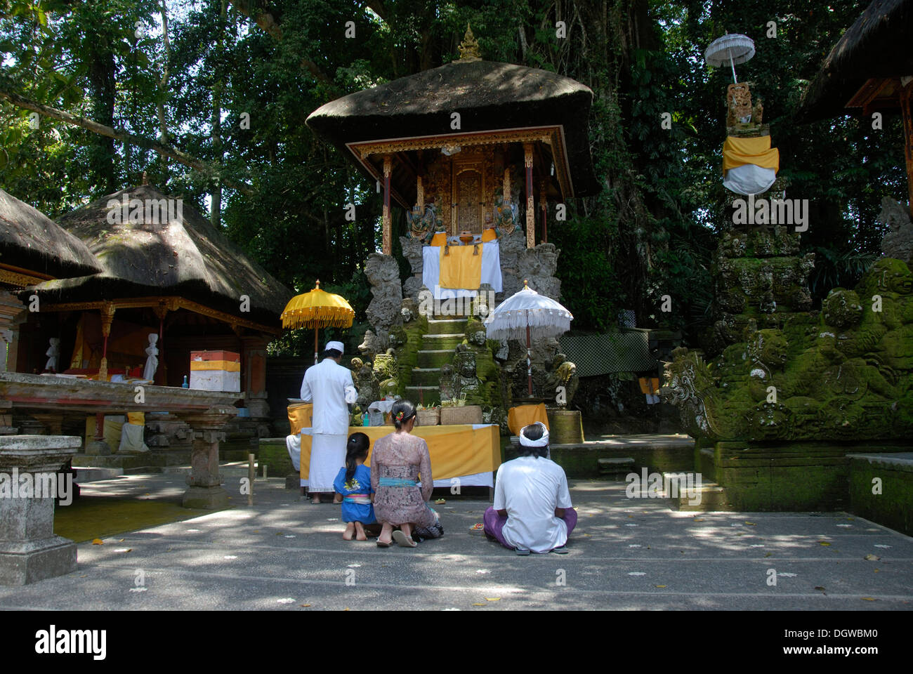 Bali Hinduism, devout family kneeling in front of shrine, Brahmin priest in white robe, Pura Griya Sakti Temple near Ubud, Bali Stock Photo