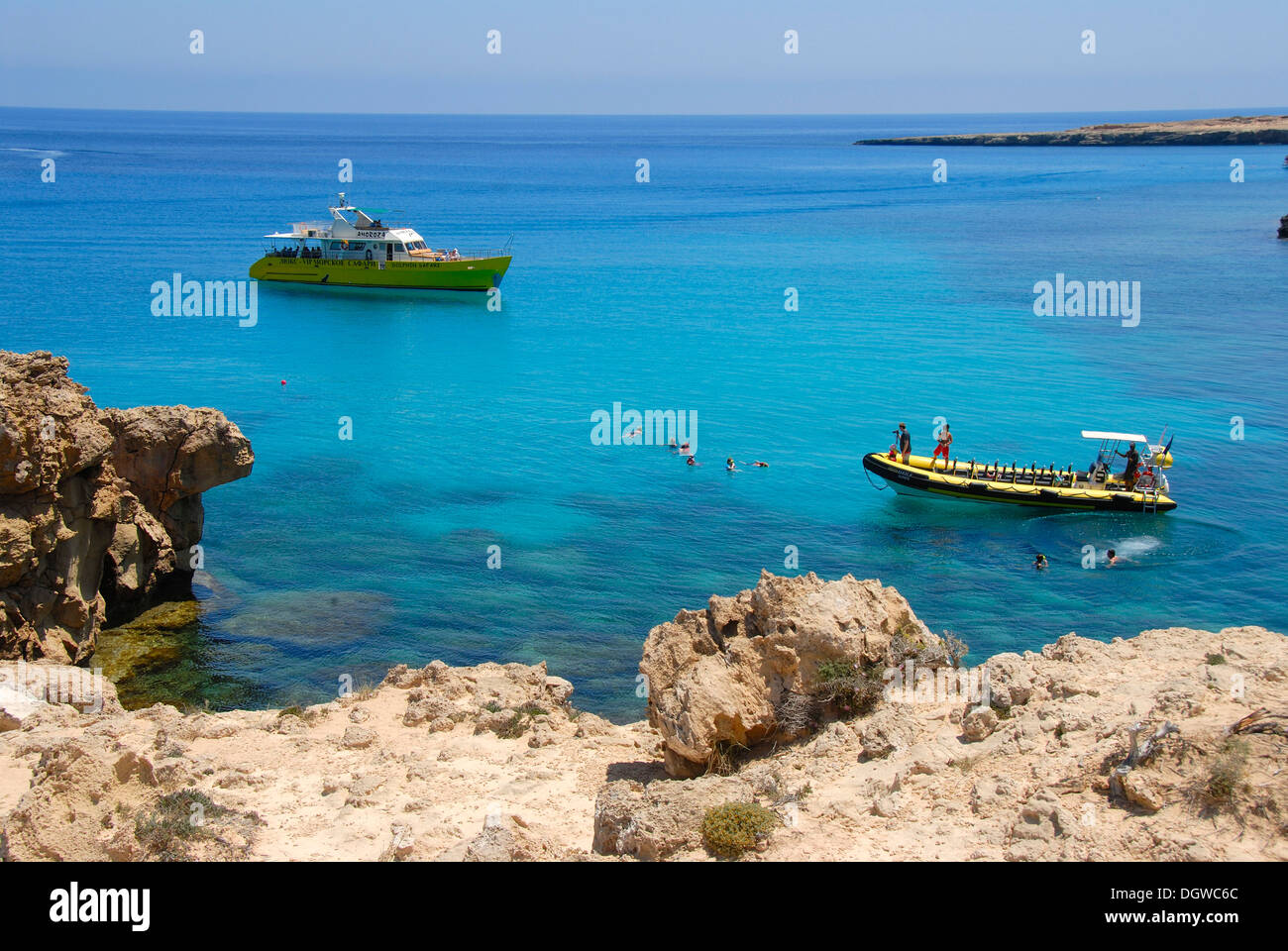 Rock coast, cliffs and blue sea with boats and swimming people, Cap Gkreko, Cape Greco in Ayia Napa, Southern Cyprus Stock Photo