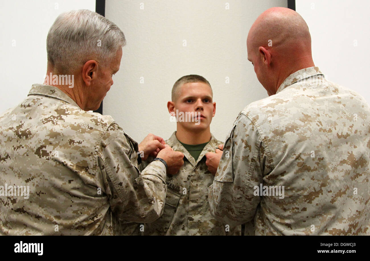 The 35th commandant of the Marine Corps, General James F. Amos, and the 17th sergeant major of the Marine Corps, Sgt. Maj. Micheal P. Barrett, promote Lance Cpl. Wesleigh M. Beckman, ordnance technician with Marine Aviation Logistics Squadron 11 (MALS-11) Stock Photo