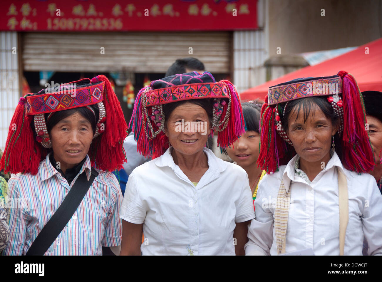 Three women of the Yi or Hani ethnic minority wearing colourful headware at a festival, Jiangcheng, Pu'er City, Yunnan Province Stock Photo