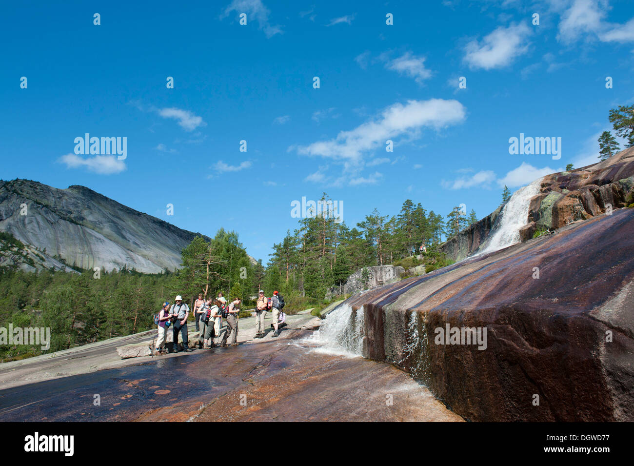 Hiking, trekking, hiking group standing at a waterfall, granite rocks