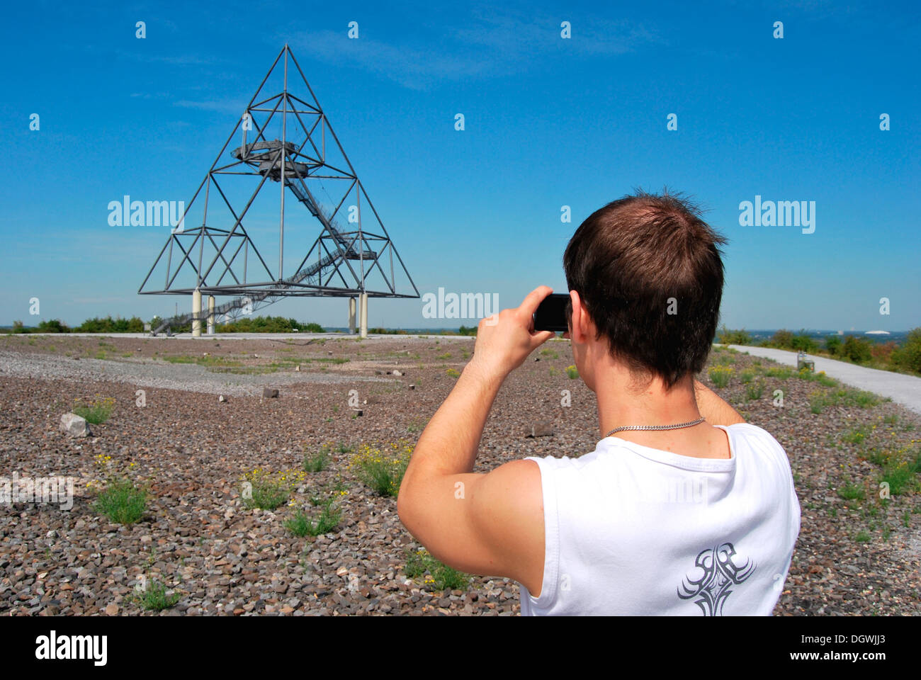 Young man taking pictures of the Tetraeder landmark, a tetrahedron made from steel, with a digital camera, industrial heritage Stock Photo
