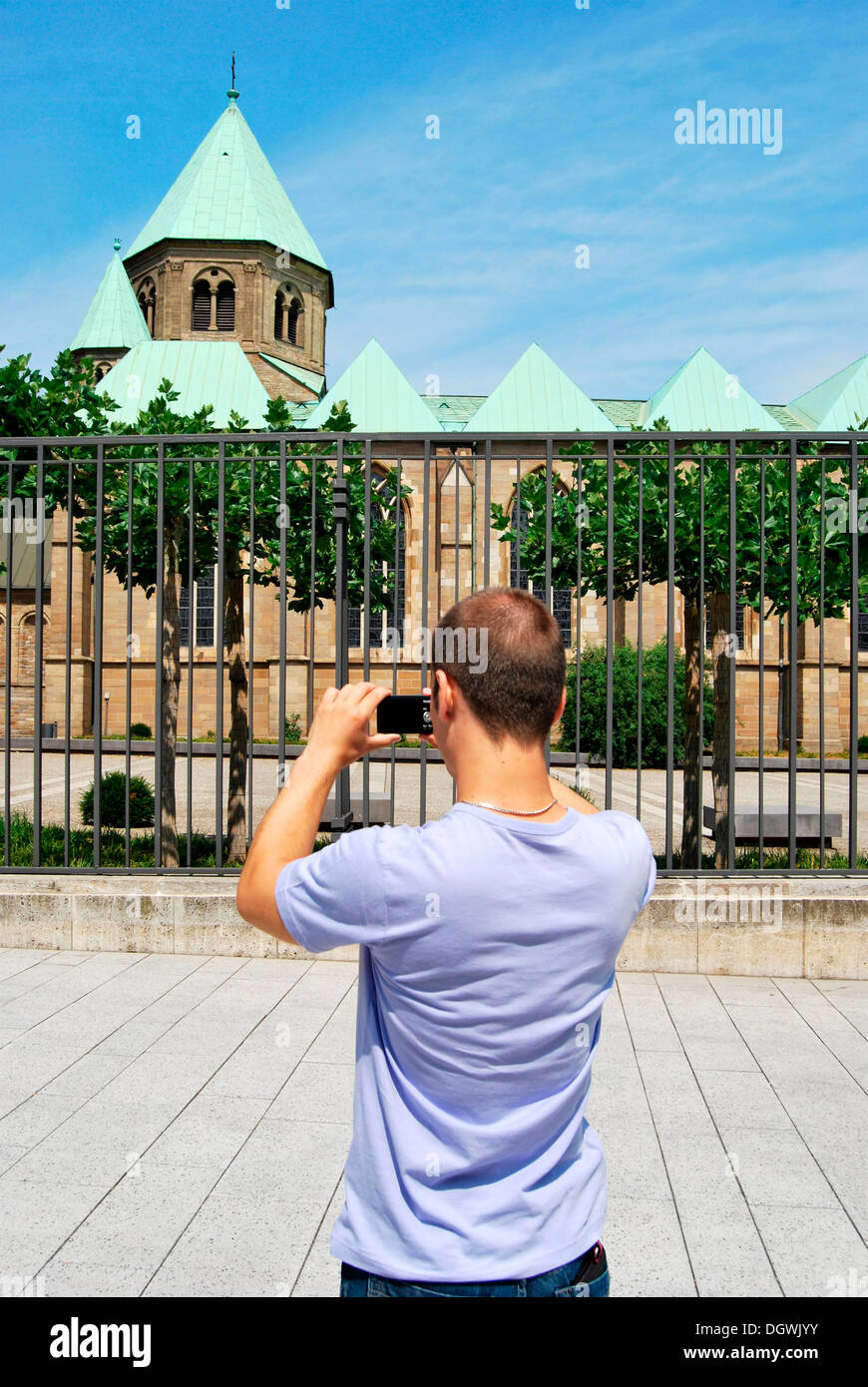 Tourist visiting the Ruhr area, young man taking pictures of the Essen Cathedral with a digital camera, Essen European Capital Stock Photo