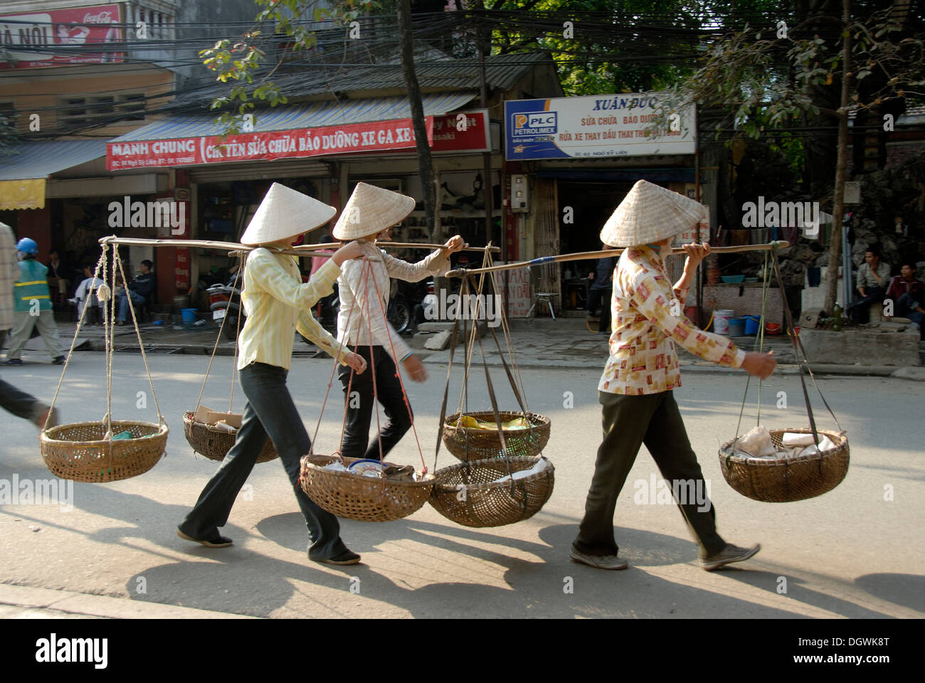 Three Vietnamese woman wearing rice hats and carrying baskets on their shoulders, Hanoi, Vietnam, Asia Stock Photo