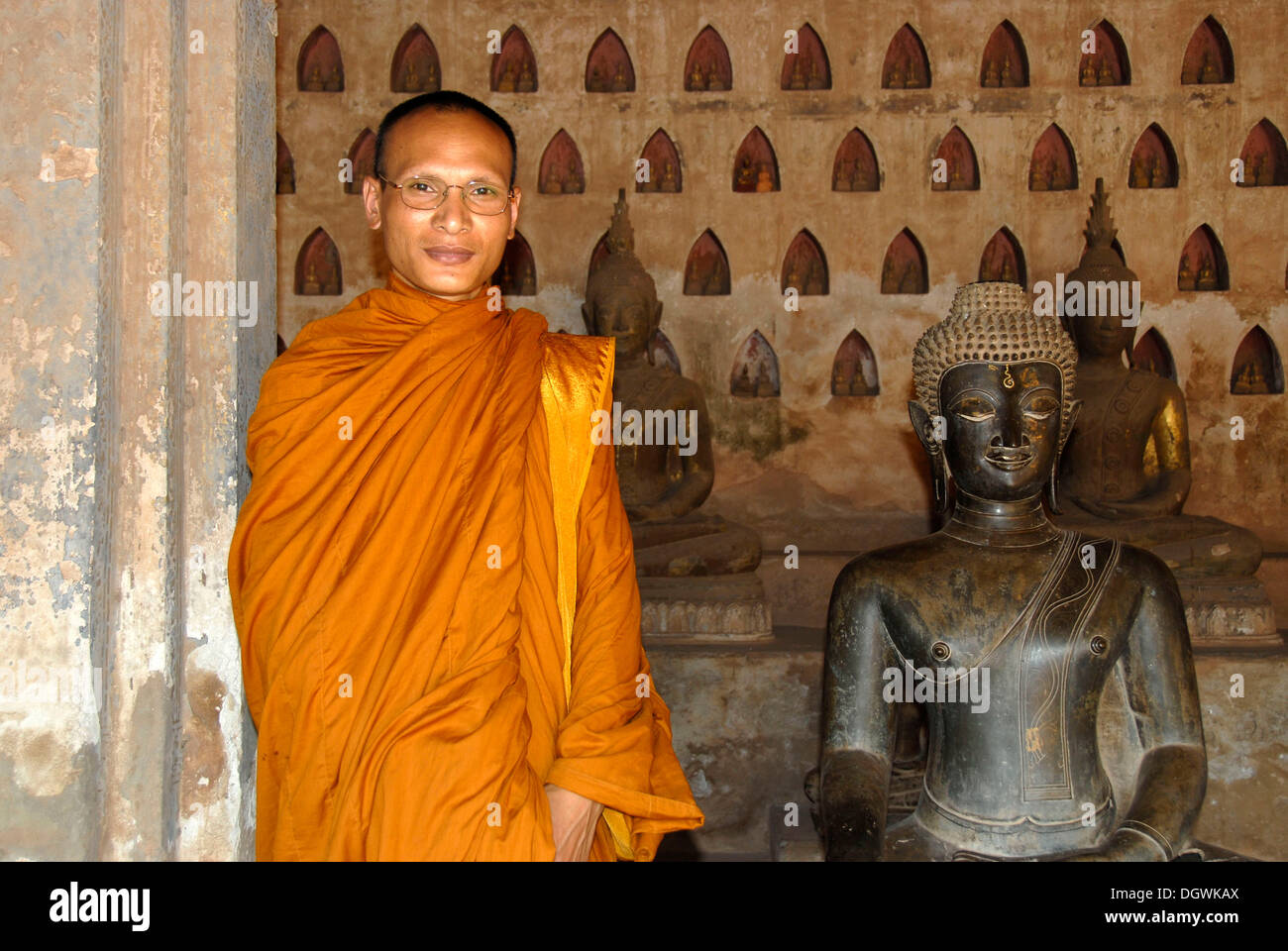 Theravada Buddhism, monk dressed in orange robes, old bronze Buddha statue, Wat Sisaket, Vientiane, Laos, Southeast Asia, Asia Stock Photo