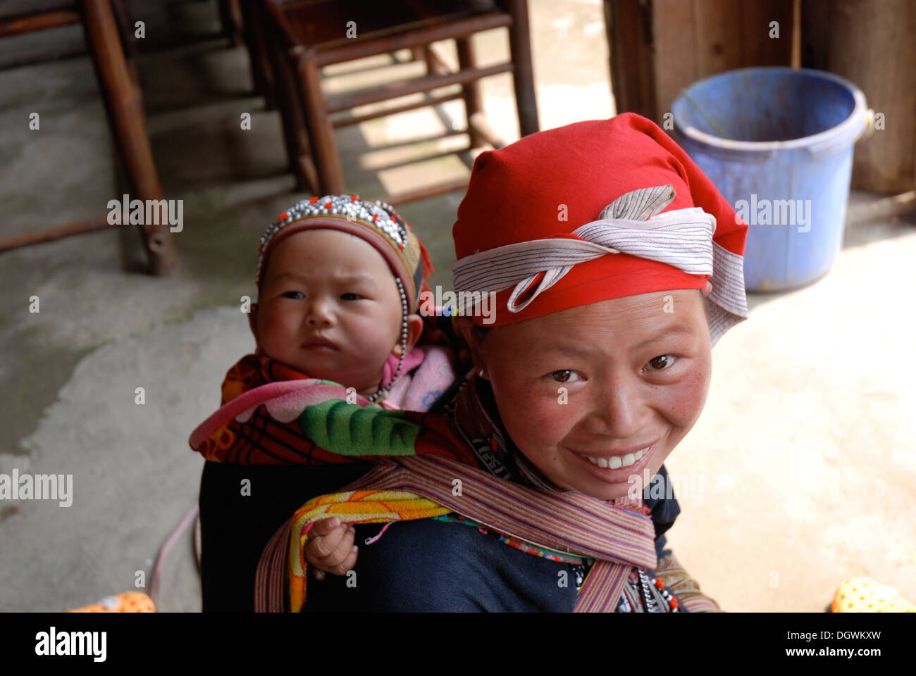 Red dao tribes woman with child strapped to her back in Ta Phin village, near Sapa in Vietnam Stock Photo