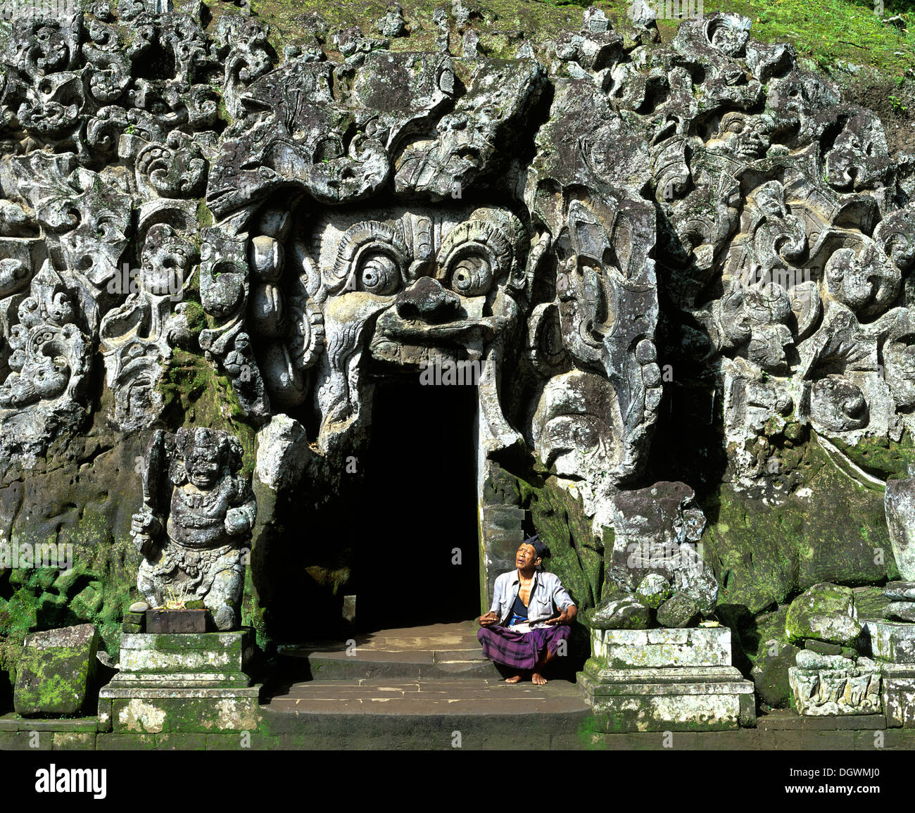 Balinese man sitting at the entrance to the Goa Gajah or Elephant Cave, cave temple, Bedulu, Bali, Südostasien, Indonesia Stock Photo