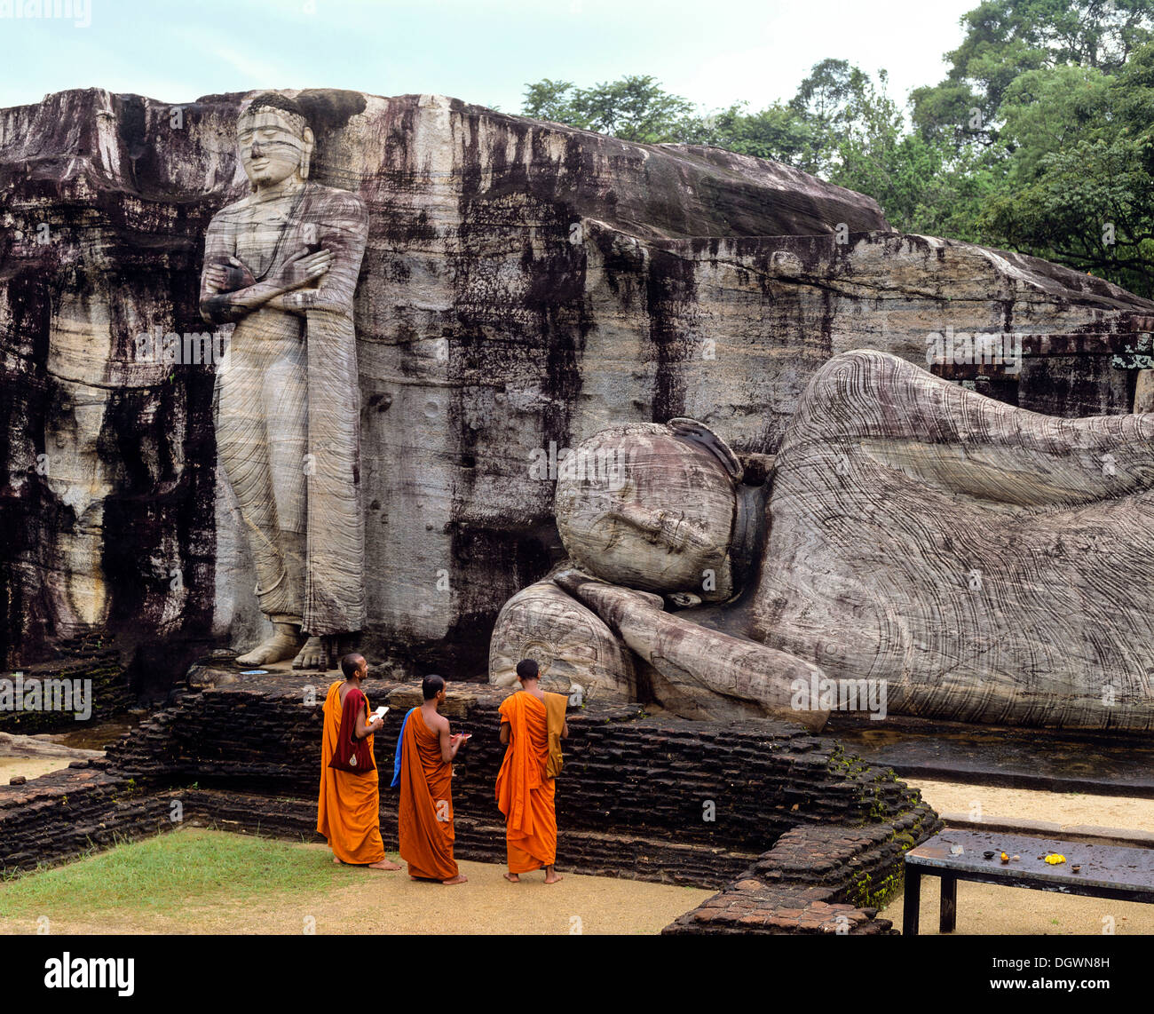 Reclining Buddha, entrance to Nirvana, three monks standing in front of the Gal Vihara rock temple, UNESCO World Heritage Site Stock Photo