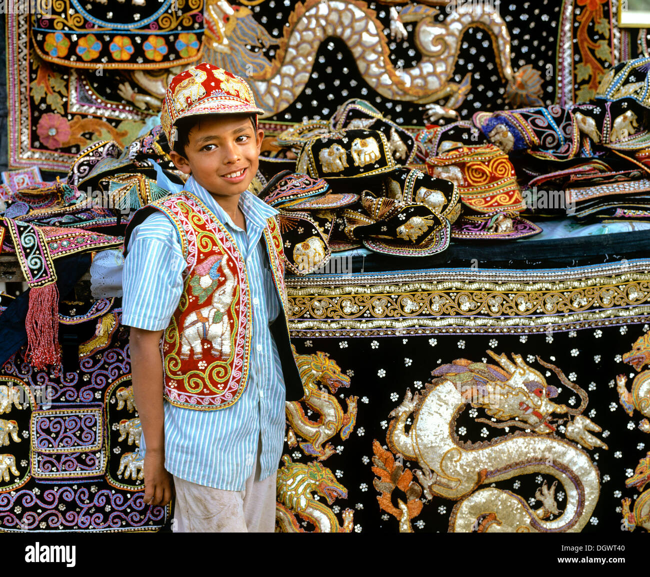 Boy with traditional textile art, tapestries and bags at a market, Tachilek, Shan State, Myanmar, Burma Stock Photo