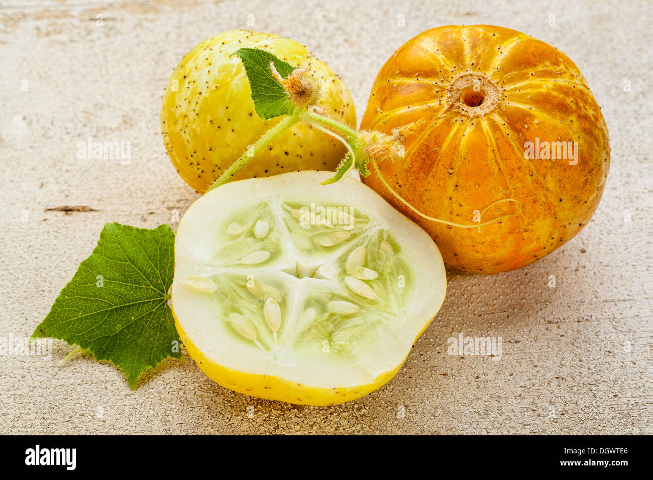 lemon (or apple) cucumbers with cross section and leaf on rough white painted wood surface Stock Photo