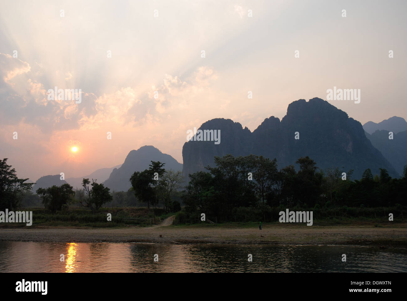 A stunning sunset over Nam song river in Vang Vieng, Laos. This atmospheric shot has  a reflection of the sun in the river Stock Photo
