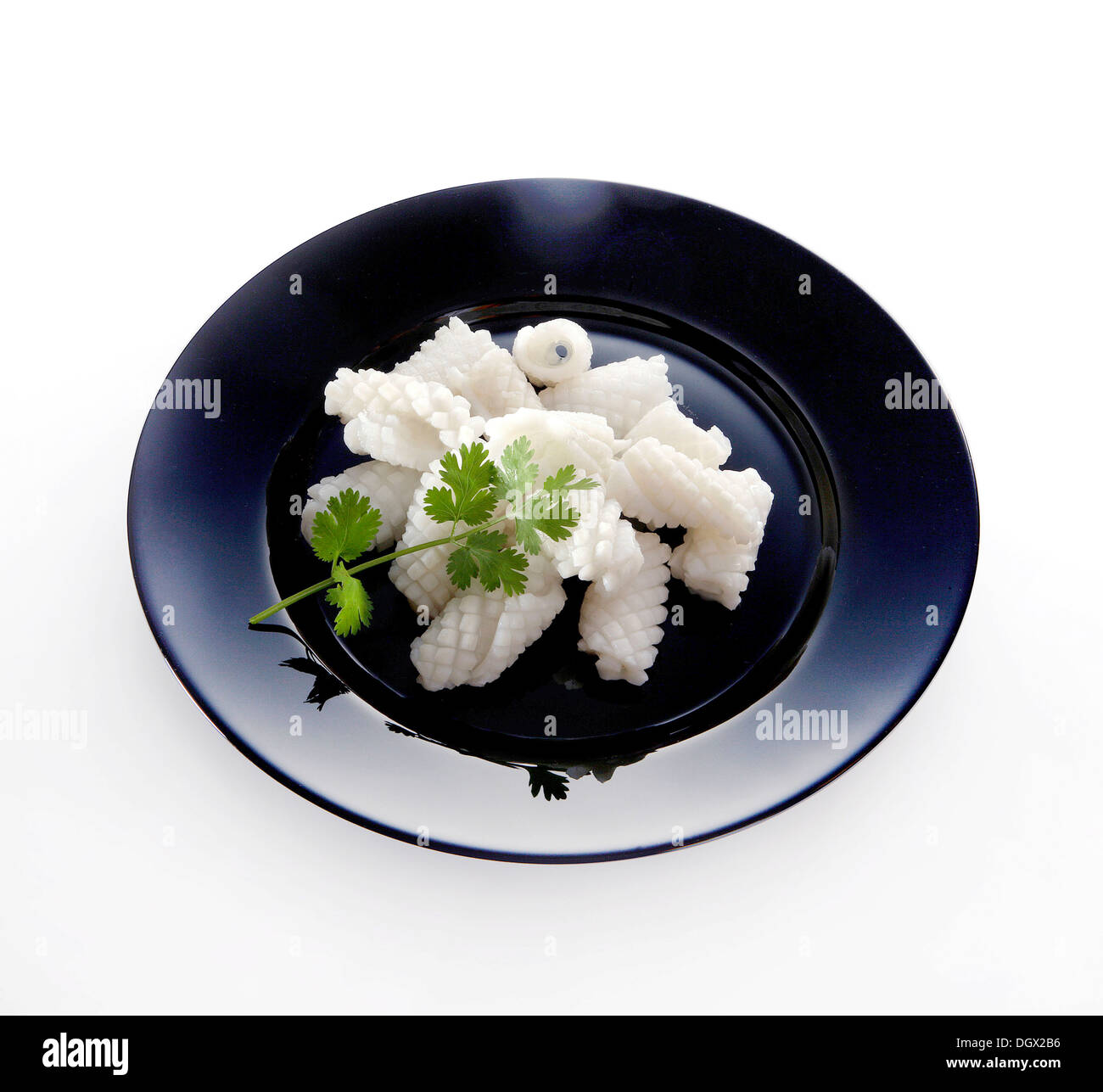 Industrially processed calamari rolls on a black plate Stock Photo