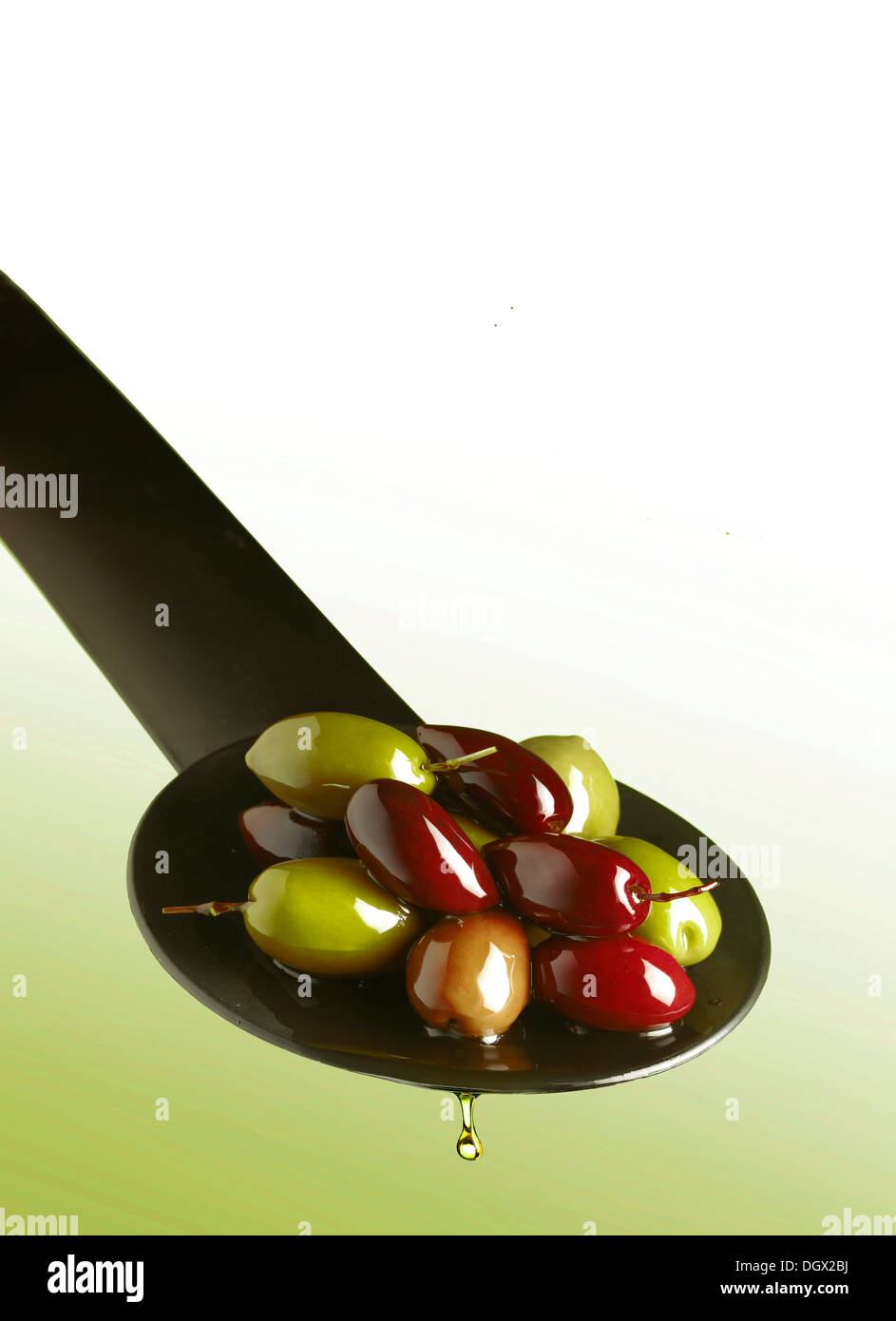 Green and black olives on a spoon with drops of oil Stock Photo