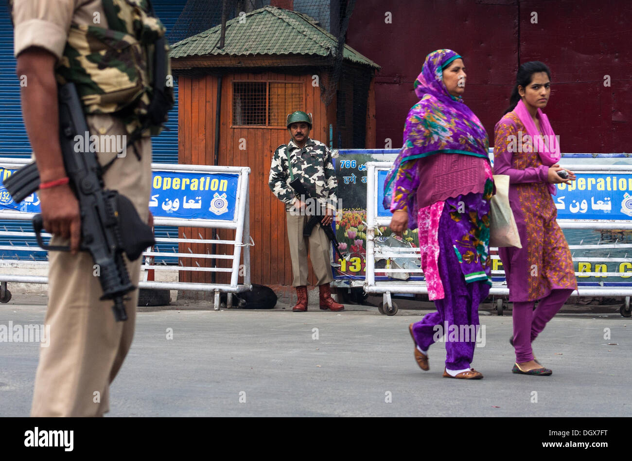 Srinagar, Indian Administered Kashmir 27 october 2013. Indian paramilitary soldiers  guard  the deserted  as kashmnir women pass by during a strike in Srinagar the summer capital of indian adminstered kashmir ,india . Large number of Indian troops were deployed to thwart anti-Indian protests in Kashmir. Indian troops landed in Kashmir  on  27 October  in kashmir  in 1947 A shutdown called by many resistance groups against the landing of the Indian army in Jammu and Kashmir this day in 1947 is being observed on Sunday.. (Sofi Suhail/ Alamy Live News) Stock Photo