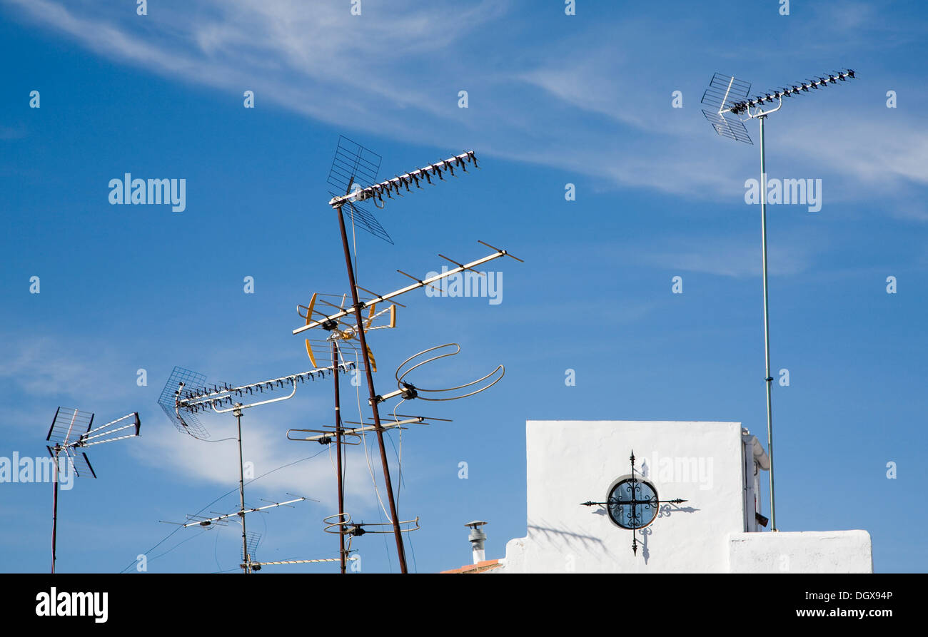 Variety of television aerials on rooftops against blue sky Spain Stock Photo