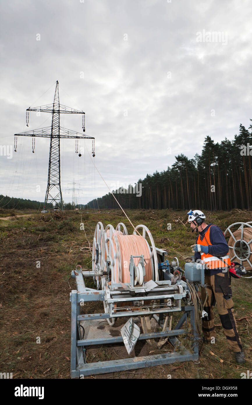 Lineman working with a wire rope hoist on a 380-kV long-distance line owned by the 50Hertz transmission system operator, track Stock Photo