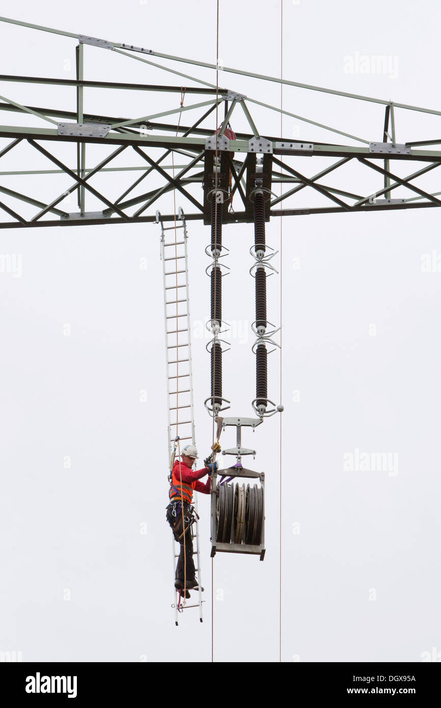 Lineman working with a wire rope hoist on a 380-kV long-distance line owned by the 50Hertz transmission system operator, track Stock Photo