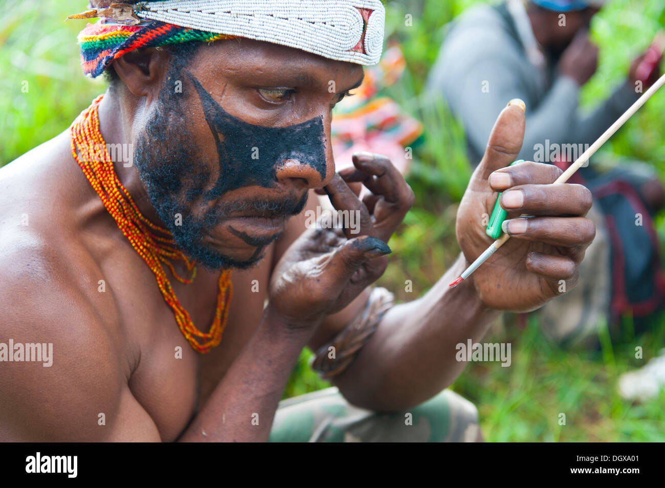 Man applying make-up for the traditional Sing Sing gathering in the highlands, Paya, Papua New Guinea Stock Photo