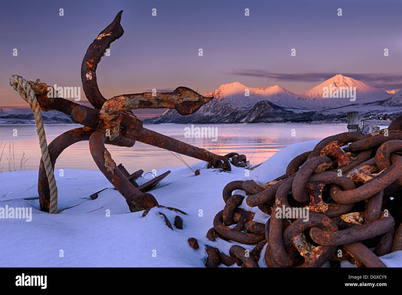 Rusty anchor in front of a fjord with a mountain range in the evening light, Tromsø, Troms, Northern Norway, Norway Stock Photo