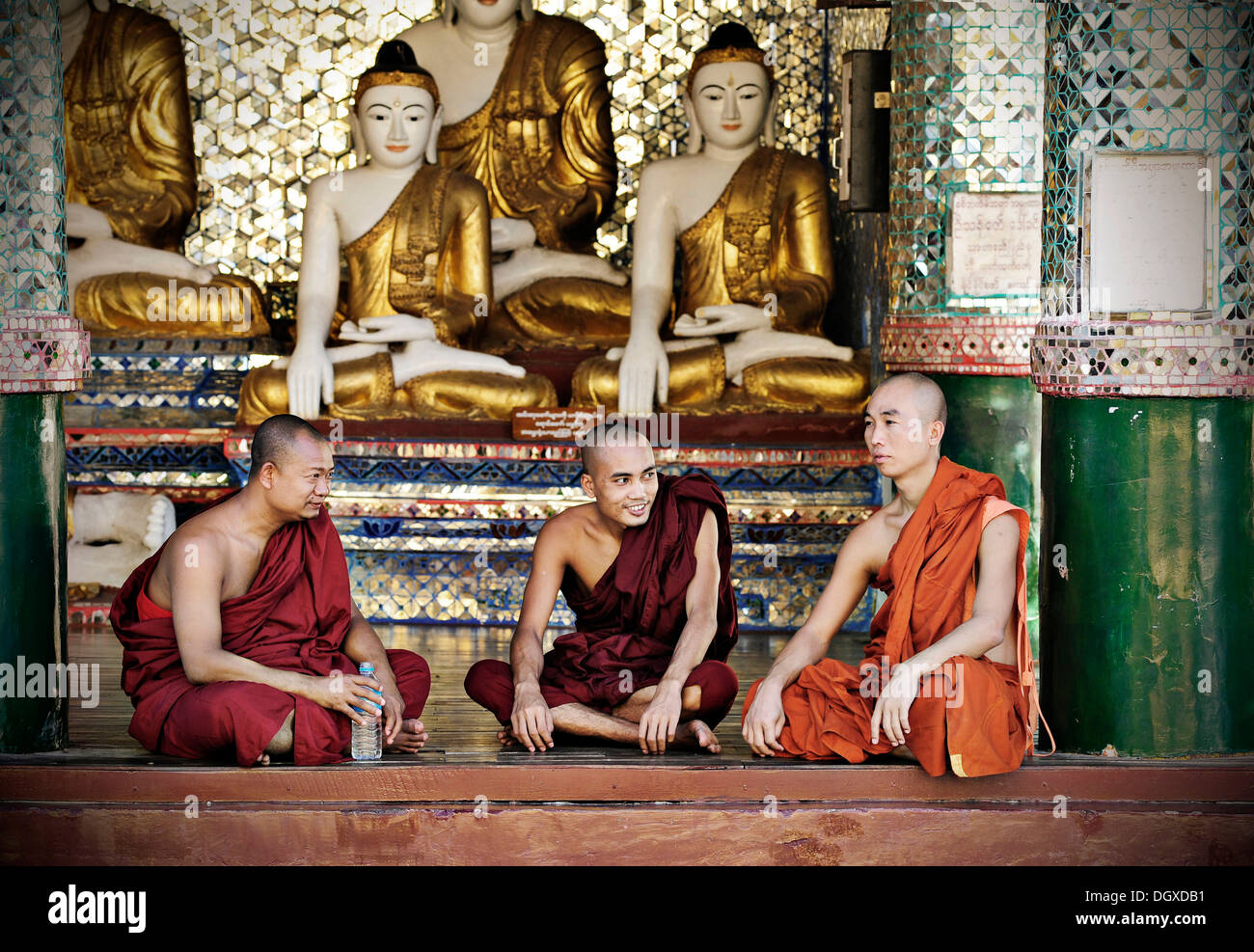 Buddhist monks sitting in front of Buddha statues in the Shwedagon Pagoda, Yangon, Burma also known as Myanmar, Southeast Asia Stock Photo