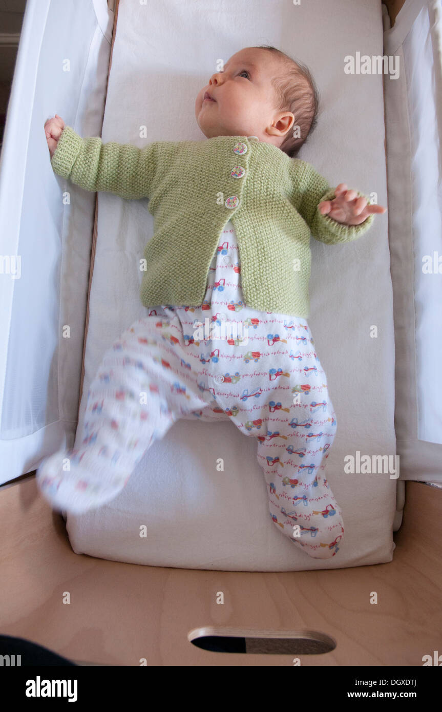 Little baby girl awake lying in her cot Stock Photo Alamy