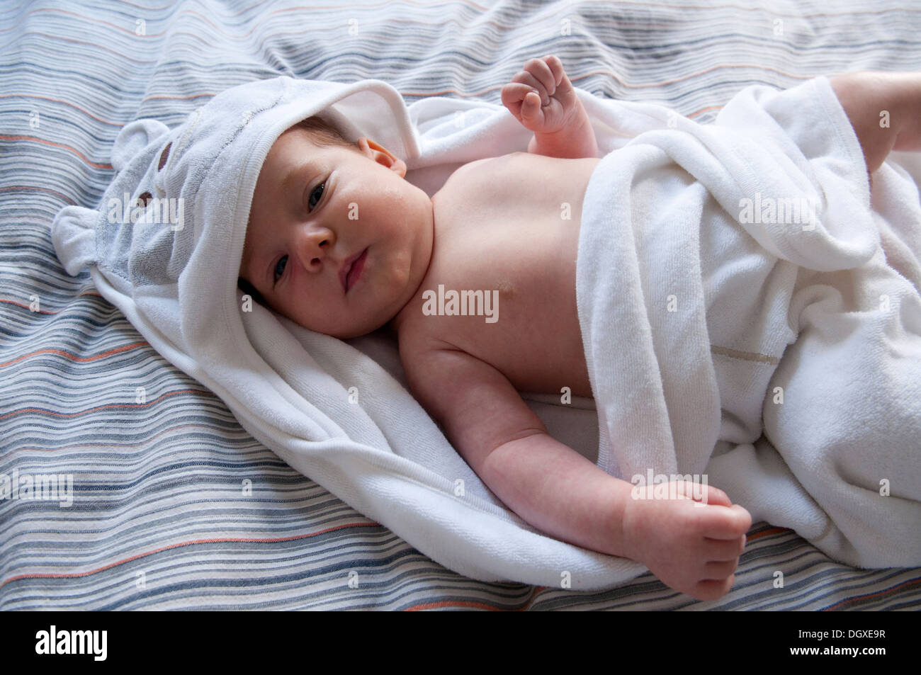 Little baby girl wrapped up in a white hooded towel Stock Photo